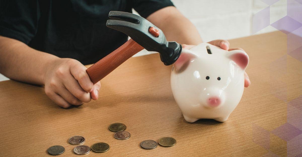 A man smashes a piggy bank with a hammer
