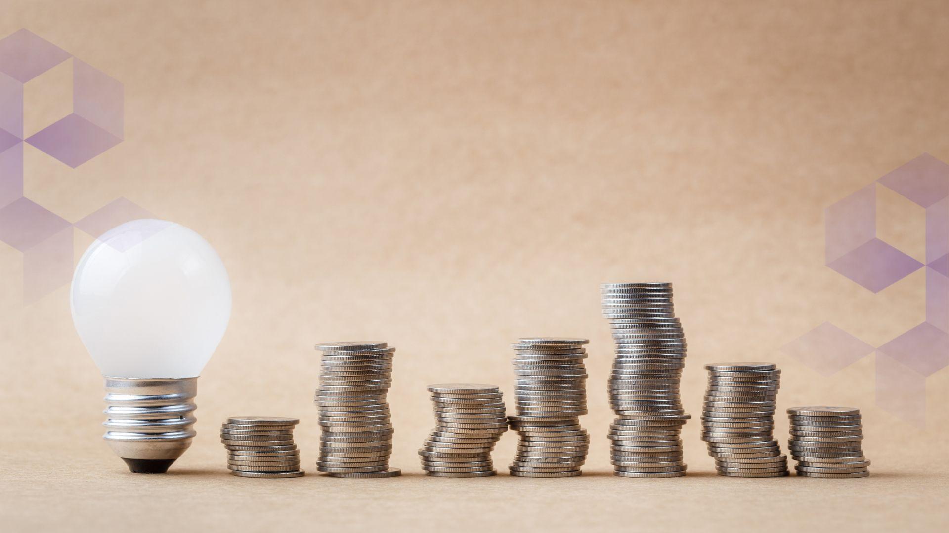 Stacks of coins in a row, with a lightbulb on the left hand side